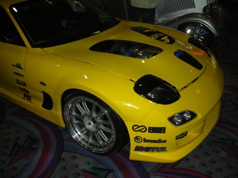 1998 Ford Crown Victoria - Front quarter of a yellow sports car with vented hood, mesh alloy wheels, and Brembo and Motul sponsor decals on the bumper.