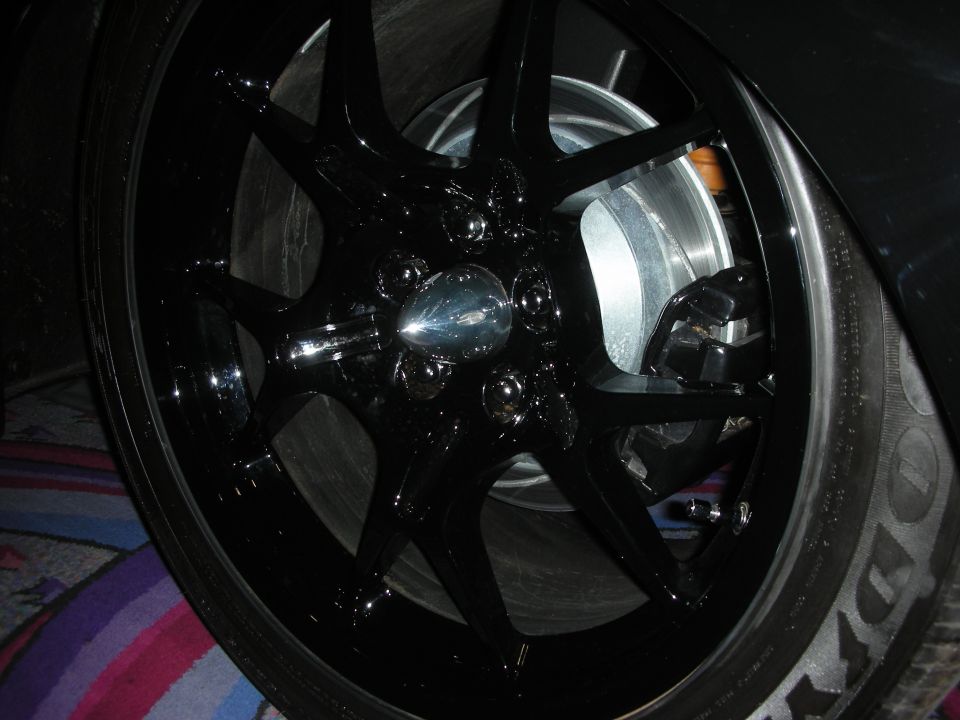 Close-up of a black multi-spoke alloy wheel with chrome center cap on a low-profile tire