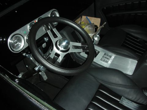 1998 Ford Crown Victoria - Custom car interior showing black leather seats, a brushed-metal center console and gauges, and a three-spoke steering wheel.