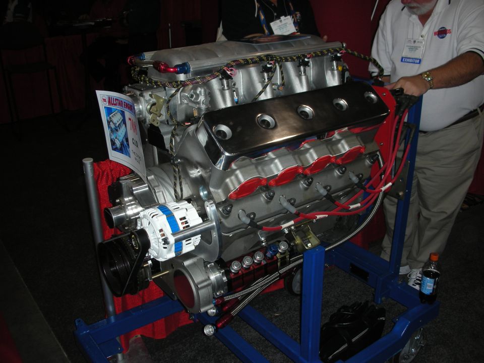Polished V8 crate engine on a blue engine stand at an indoor show