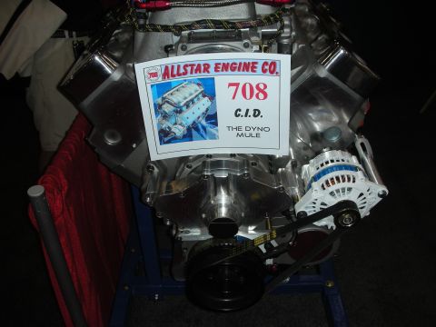 1998 Ford Crown Victoria - polished engine on a blue stand displaying an 'Allstar Engine Co. 708 C.I.D. The Dyno Mule' placard.