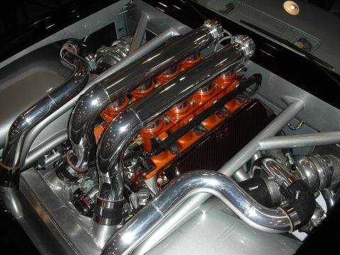 1998 Ford Crown Victoria - custom engine bay showing two polished intake runners over an orange-painted engine flanked by twin turbochargers and chrome piping.