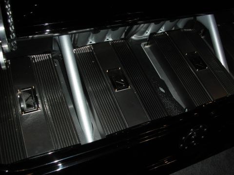 1998 Ford Crown Victoria - trunk-mounted audio install showing three finned black amplifiers arranged on a polished black surface under accent lighting.