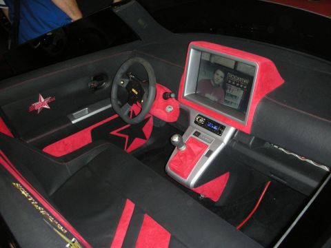 1998 Ford Crown Victoria - black-and-red custom car interior with star motifs, suede steering wheel, and a dash-mounted video screen showing a Rockstar logo.