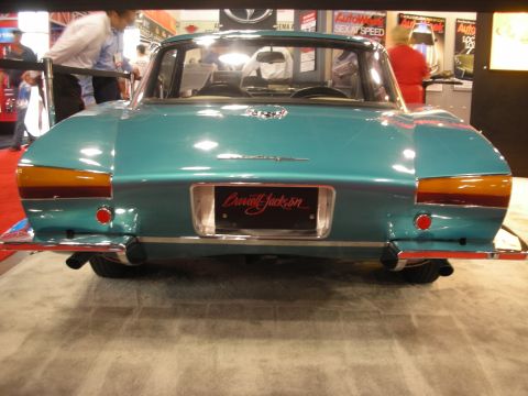 1998 Ford Crown Victoria - Rear view of a teal custom car displaying a Barrett-Jackson license plate, dual exhaust tips, and chrome bumper at a show.