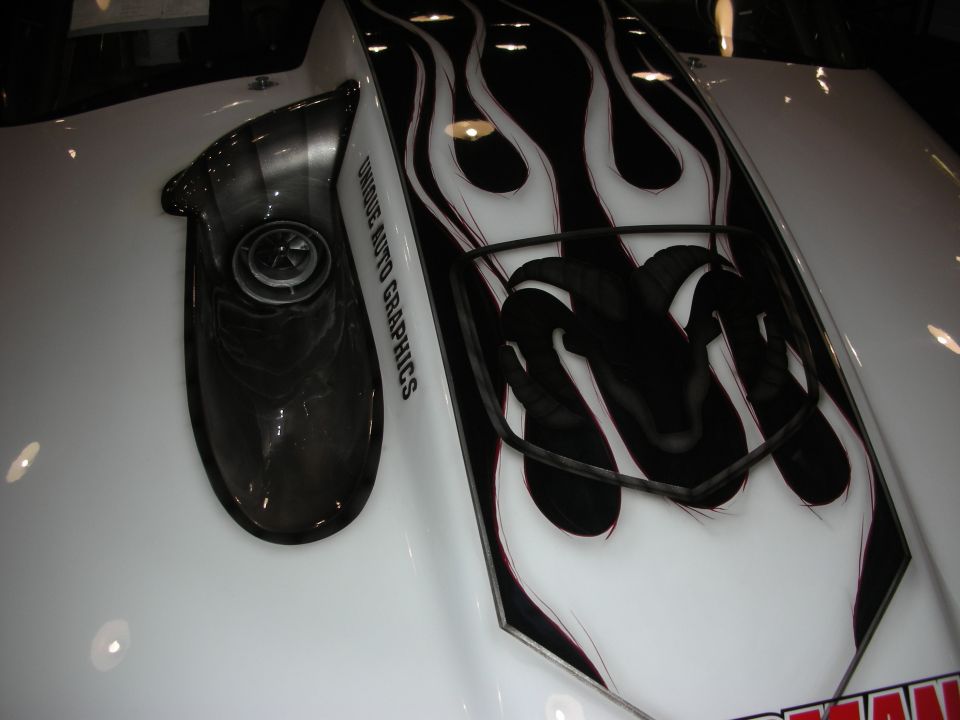 White car hood with black flame graphics and a Dodge Ram head logo, scoop