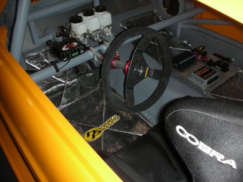 1998 Ford Crown Victoria - gutted race car interior featuring a roll cage, MOMO suede wheel, twin master cylinders, and a Cobra-branded racing seat.
