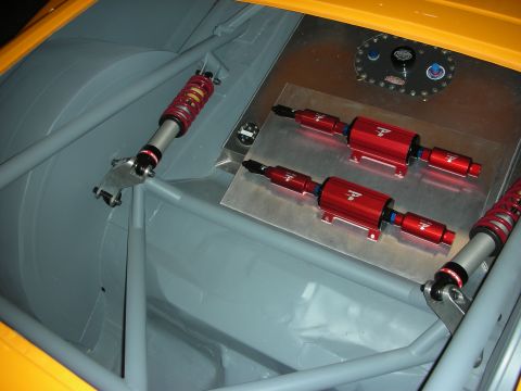 1998 Ford Crown Victoria - rear of a stripped race car showing the roll cage, twin red inline fuel filters, coilover shocks, and an aluminum fuel cell.