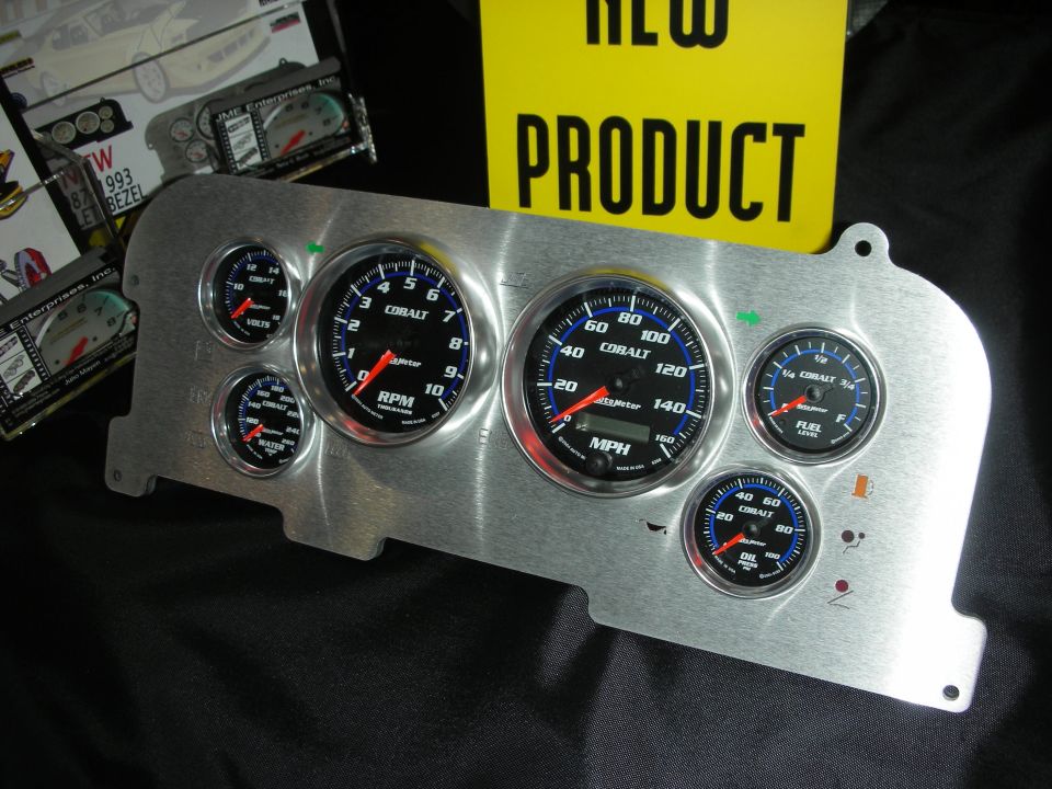 Aftermarket aluminum dash gauge panel fitted with black Cobalt gauges beside a New Product sign