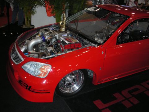 1998 Ford Crown Victoria - red drag-style coupe with its hood removed exposing a turbocharged engine, polished wheels and ERL Performance graphics at a show.