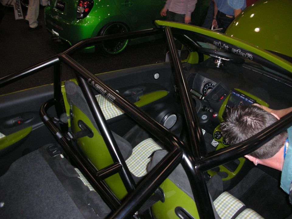 Stripped green car interior with black roll cage and checkered cloth seats