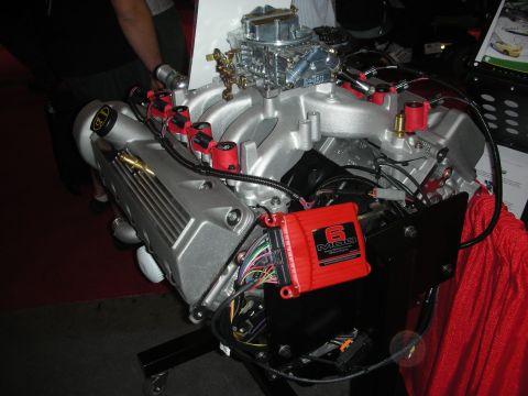 1998 Ford Crown Victoria - crate engine with a silver intake, four-barrel carburetor, red plug wires and a red MSD 6 ignition box on a display stand.
