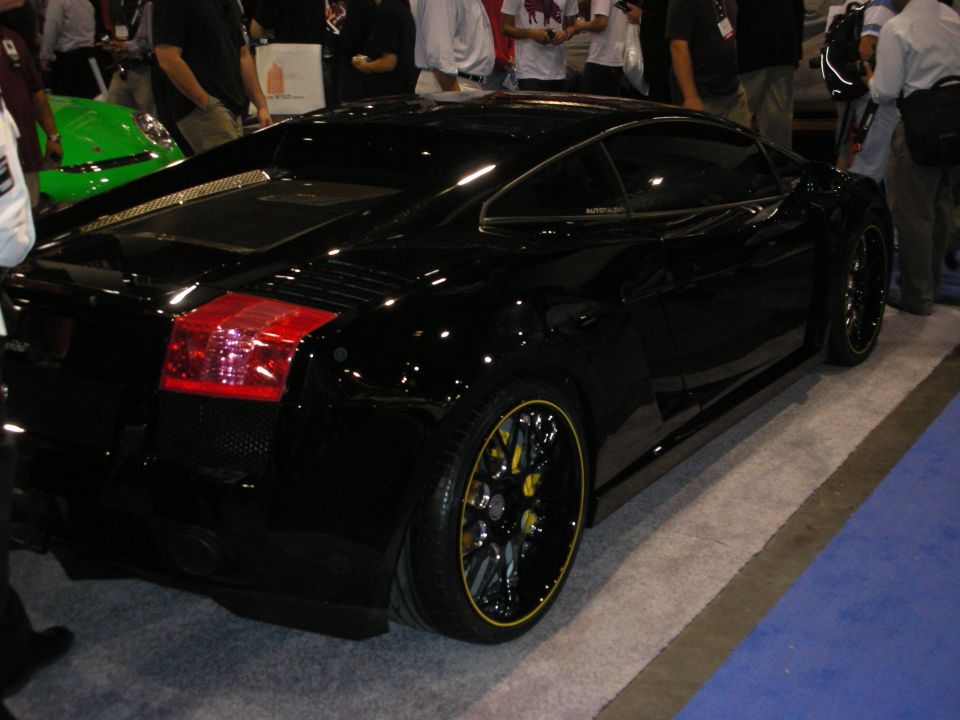 Black Lamborghini Gallardo coupe rear three-quarter on black-and-gold wheels at a show