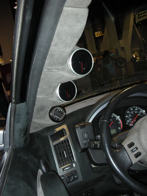 1998 Ford Crown Victoria - suede A-pillar pod holding two auxiliary gauges beside the steering wheel and leather-trimmed dash of a customized car interior.