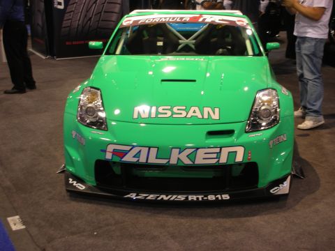 1998 Ford Crown Victoria - green Nissan 350Z race car shown head-on with Nissan, Falken and Azenis RT-615 graphics and a low front splitter.