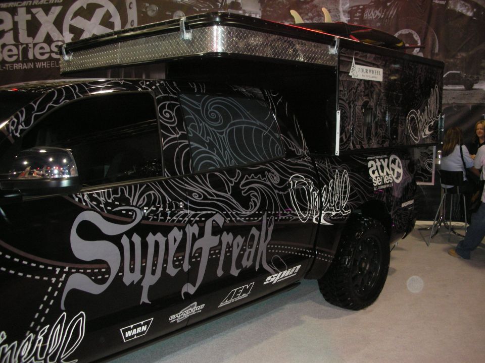 Black truck with white SuperFreak pinstripe-style graphics and ATX wheels at a booth