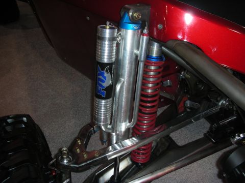 1998 Ford Crown Victoria - close-up of an off-road suspension corner showing a black Fox bypass shock, a red coilover spring and a chromoly control arm.