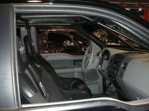 1998 Ford Crown Victoria - Interior of a custom show car showing a chrome-moly roll cage, single racing bucket seat and gray dashboard.