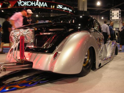1998 Ford Crown Victoria - Rear three-quarter view of a chopped custom coupe in black and silver with flame graphics, displayed on a ramp at an indoor show.