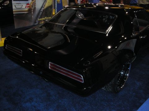 1998 Ford Crown Victoria - Rear three-quarter view of a glossy black custom muscle-car coupe with horizontal taillights on a blue show carpet.