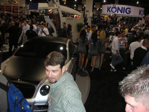 1998 Ford Crown Victoria - Busy indoor trade-show booth featuring a silver custom car and Konig wheel signage with people in the aisle.