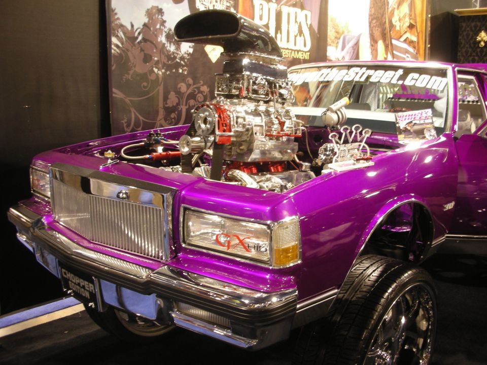 Purple custom car with open hood showing chrome blown V8 engine at a show