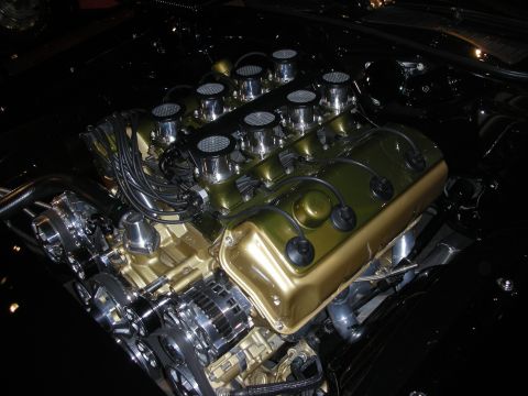 1998 Ford Crown Victoria - gold-painted V8 engine fitted with individual velocity stacks and polished accessories shown in a dark engine bay.