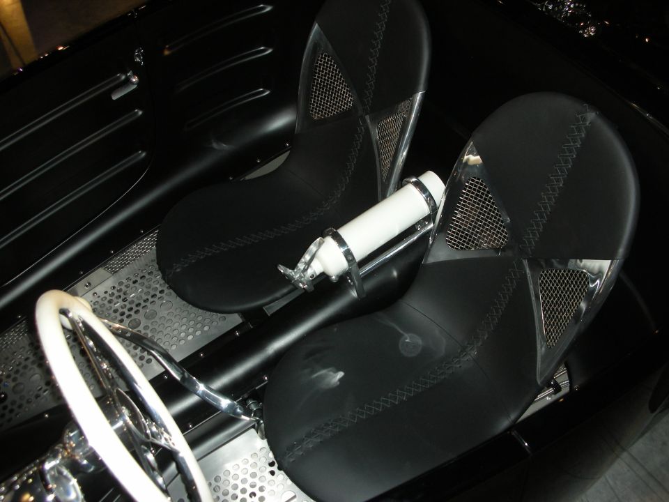 Two black mesh-trimmed bucket seats and white steering wheel in an open custom car