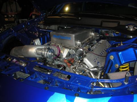 1998 Ford Crown Victoria - Engine bay of a blue car fitted with a large turbocharger and a ProForma intake plenum under blue lighting.