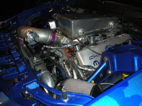 1998 Ford Crown Victoria - Turbocharged engine in a blue car with Mopar-branded aluminum valve covers and braided lines under blue lighting.