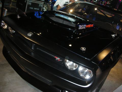 1998 Ford Crown Victoria - tight front-end shot of a black Dodge Challenger shows quad headlights, an R/T badge, and a hood scoop labeled 392 HEMI.