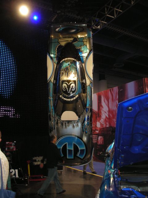 1998 Ford Crown Victoria - custom Dodge Charger body is stood vertically on display, airbrushed in blue with a Ram's-head emblem, Charger script, and a Mopar logo.