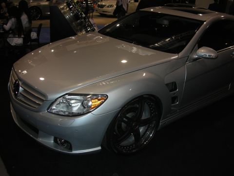 1998 Ford Crown Victoria - silver Mercedes-Benz CL coupe with oversized black multi-spoke wheels sits on a show floor with other cars behind it.