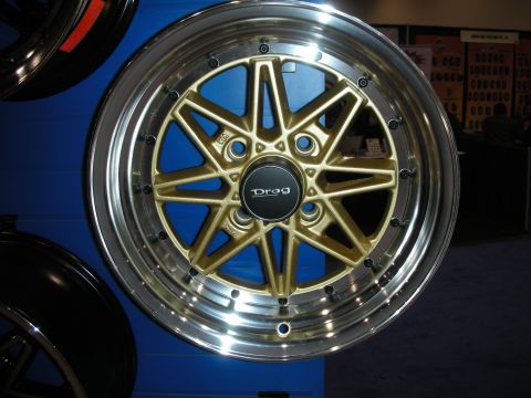 1998 Ford Crown Victoria - gold Drag-brand multi-spoke alloy wheel with a polished lip is displayed against a blue booth wall.