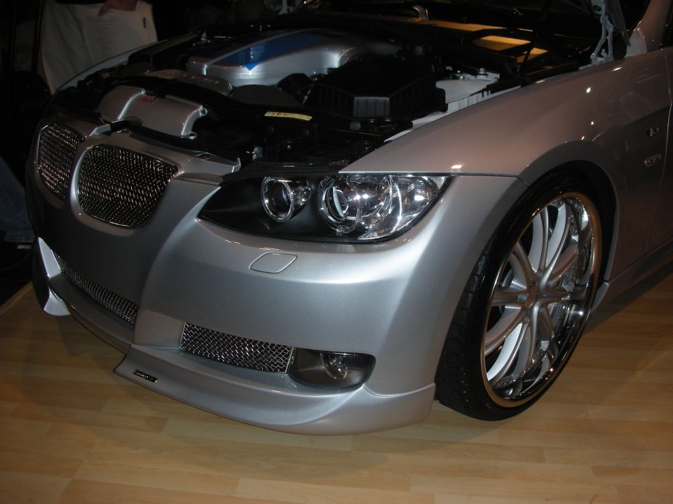 Silver BMW 3 Series coupe front with custom bumper, open hood, and chrome wheels