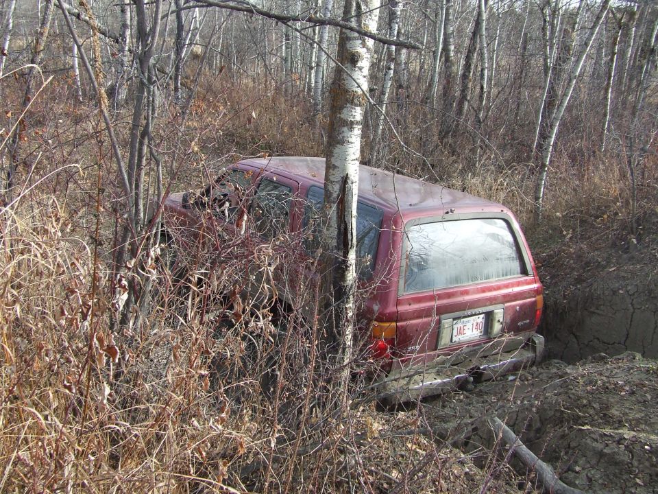 Red SUV stuck in muddy ditch, rear view showing license plate JAE-142