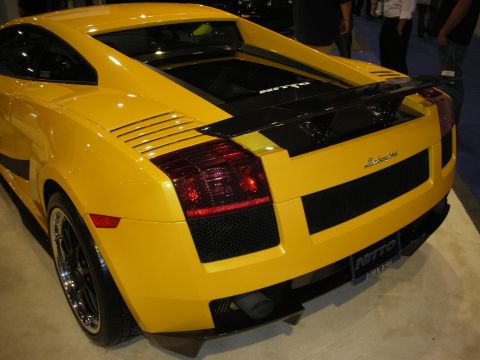 1998 Ford Crown Victoria - Rear three-quarter view of a yellow Lamborghini Gallardo with chrome wheels and a carbon rear deck at an auto show.