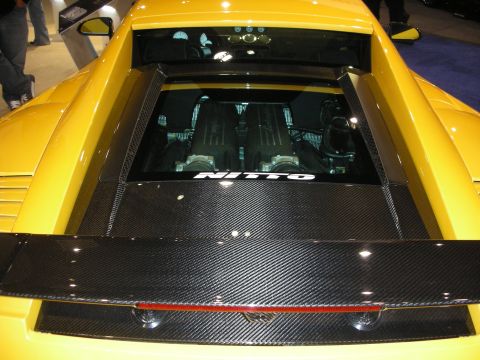 1998 Ford Crown Victoria - View of a yellow Lamborghini's glass-covered V engine bay and carbon rear wing, the glass lettered Nitto.