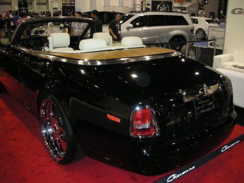 1998 Ford Crown Victoria - Rear of a black Rolls-Royce drophead convertible with a teak rear deck and chrome wheels on a red carpeted show stand.