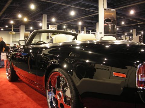1998 Ford Crown Victoria - Side view of a black convertible with chrome multi-spoke wheels and Carlsson script badging at an auto show.