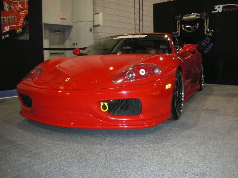 1998 Ford Crown Victoria - Front three-quarter view of a red Ferrari 360 with black mesh grilles and a yellow tow hook on a show stand.