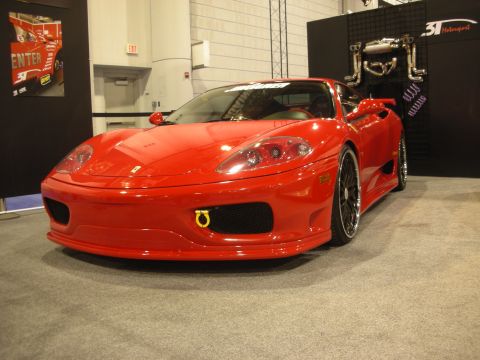 1998 Ford Crown Victoria - Front view of a red Ferrari 360 with black multi-spoke wheels and a yellow tow hook at an auto show booth.