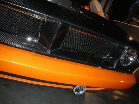 1998 Ford Crown Victoria - Close-up of an orange car's carbon-fiber front fascia with black mesh intake scoops and a round foglight.