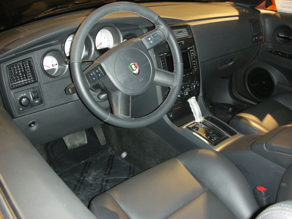Black leather interior of a car with round gauges, console shifter and crest steering wheel badge