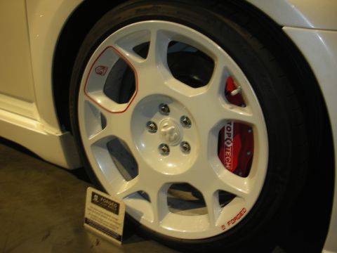 1998 Ford Crown Victoria - Close-up of a glossy white forged wheel fitted with a red Topotech big-brake caliper on a silver vehicle at an indoor show.