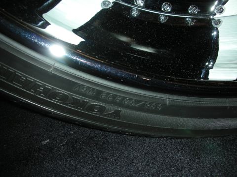 1998 Ford Crown Victoria - Detailed shot of a Yokohama tire sidewall mounted on a polished chrome wheel resting on carpet.
