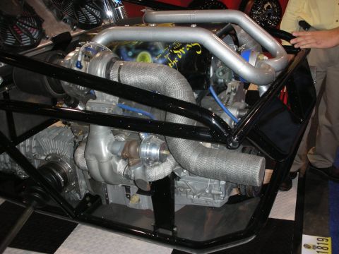 1998 Ford Crown Victoria - twin-turbocharged engine with heat-wrapped headers mounted in a black tubular space-frame chassis at a show.
