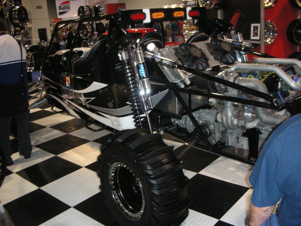 Black off-road sand buggy with paddle tires on checkered floor