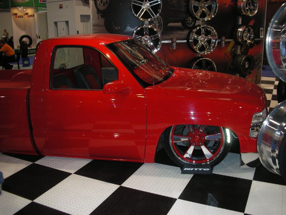 Slammed red pickup truck on Nitto tires with chrome wheels