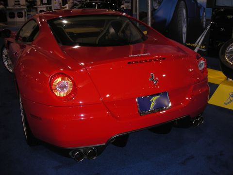 1998 Ford Crown Victoria - Rear three-quarter view of a red Ferrari coupe with round taillights, the prancing horse badge and quad exhaust tips.